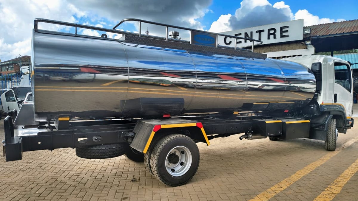 Isuzu FRR90N with an insulated stainless-steel milk tanker, side view.