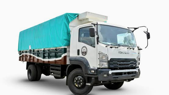Isuzu FVR34P in white with a cargo body under a green tarpaulin, side three-quarter view.