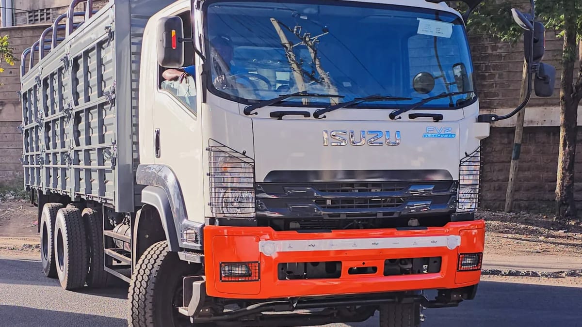 Isuzu FVZ34 six-wheeler fitted with a high slatted livestock body and a red front bumper, front three-quarter view on a road.