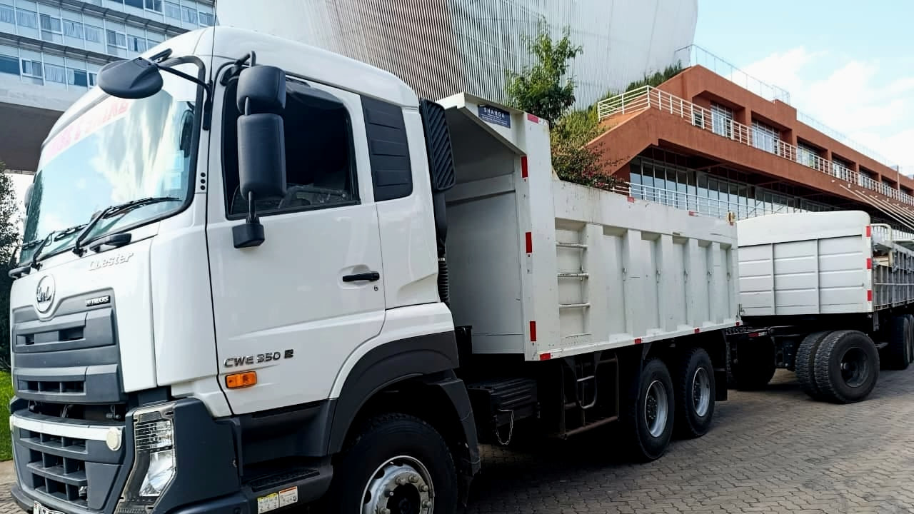 UD Quester CWE in white, front three-quarter view, carrying a tipper body and drawing a trailer, with the CWE 350 E badge on the cab door.